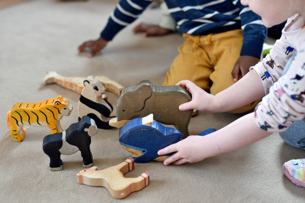 Kinder spielen mit bunten Holzfiguren auf dem Teppich