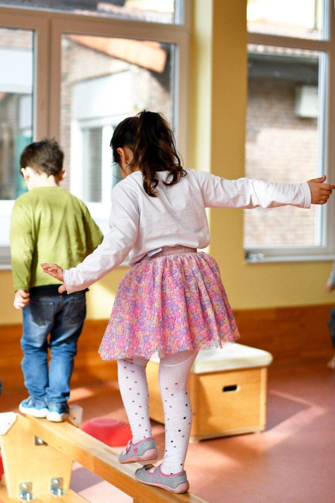 Kinder balancieren auf Holzbalken in der Turnhalle